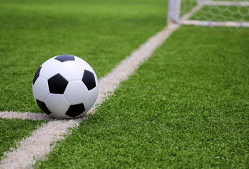 Fototapeta na wymiar Soccer football in Goal net with green grass field