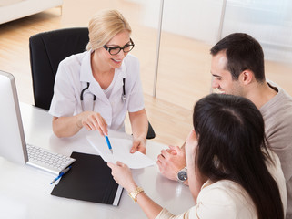 Happy Doctor Discussing With Couple