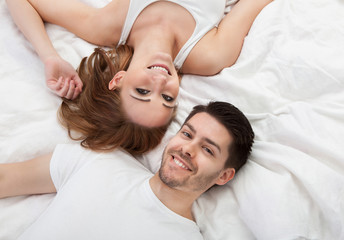 Obraz na płótnie Canvas Portrait of happy young couple lying on bed