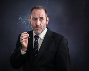 Mature businessman smoking a cigarette