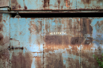 rusty metal door with the words not to smoke