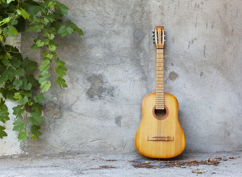 old classic guitar standing against grungy wall