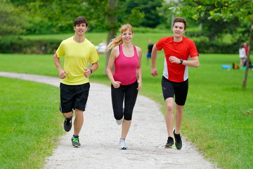 Front view of three athletes jogging in the park