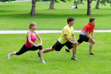 Group of three young health athletes doing stretching exercise