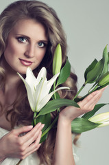 Beautiful young woman with white lily on background