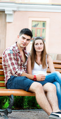 Young couple sitting on bench on street