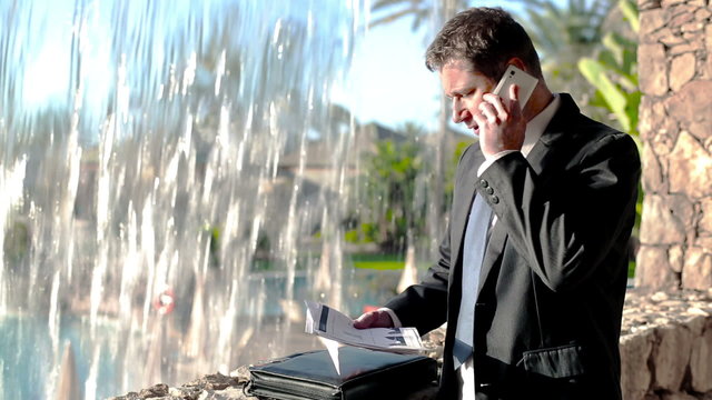 Businessman with cellphone working by the waterfall on his vacat