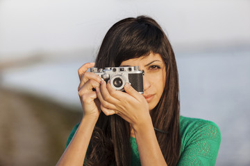 brunette girl with retro camera by the sea