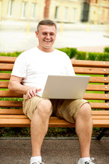 Fototapeta premium Man with laptop sitting on bench