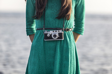 brunette girl with retro camera by the sea
