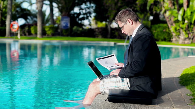 Businessman with laptop and documents on his vacation by the swi