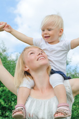 Fototapeta premium Happy mother carrying her daughter on shoulders
