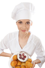 Woman chef in uniform holding tray of cookies.