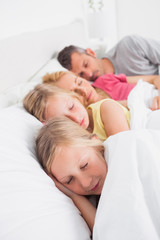 Fototapeta premium Parents sleeping with their twins in bed