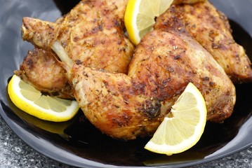Grilled chicken meat with lemon on black plate