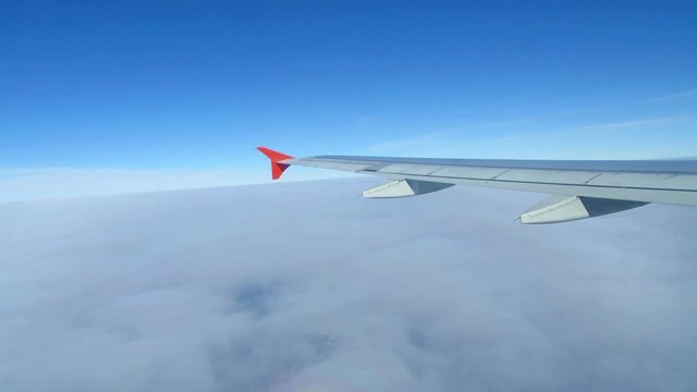 Wing of airplane flying above the clouds in the sky