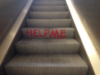 Help me Graffito auf Rolltreppe