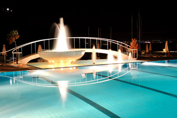 Swimming pool with fountain in night illumination at the luxury