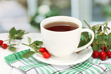 cup of tea with hip roses, on wooden table