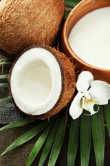 Coconut with leaves and flower, on grey wooden background