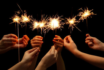 beautiful sparklers in hands on black background. - Powered by Adobe