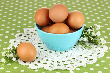 Eggs in bowl on green tablecloth close-up