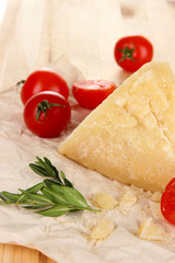 Piece of Parmesan cheese on paper on wooden table close-up