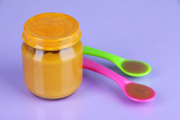 Baby food with weaning spoons on blue background