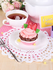 Beautiful cupcake and flavored tea on dining table close-up