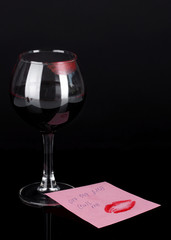 Glass of wine with lipstick imprint on dark background