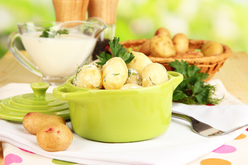 Tender young potatoes with sour cream and herbs in pan
