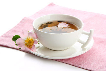 Cup of herbal tea with hip rose flowers, isolated on white