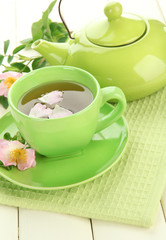 Cup and teapot of herbal tea with hip rose flowers
