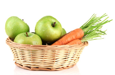 Juicy green apples and carrots with leaves in basket, isolated