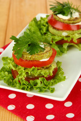 Tasty roasted marrow and tomato slices with salad leaves,