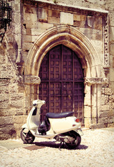 Witte vintage scooter in de buurt van middeleeuwse poort