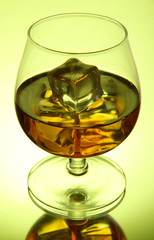 Brandy glass with ice on green background
