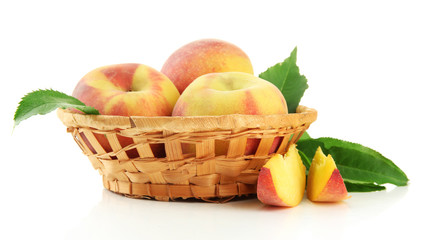Ripe sweet peaches with leaves in basket, isolated on white
