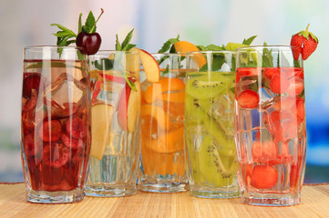 Glasses of fruit drinks with ice cubes on table in cafe