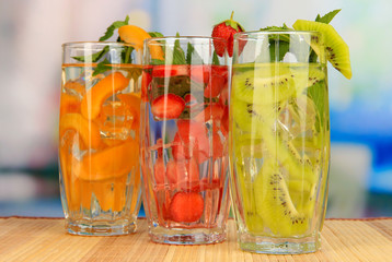 Glasses of fruit drinks with ice cubes on table in cafe