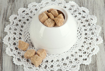 Unrefined sugar in white sugar bowl on wooden background