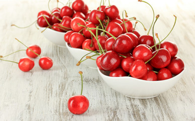 Cherry berries in bowl on wooden table close up
