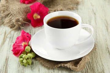 Cup of coffee and pink mallow flowers on wooden background