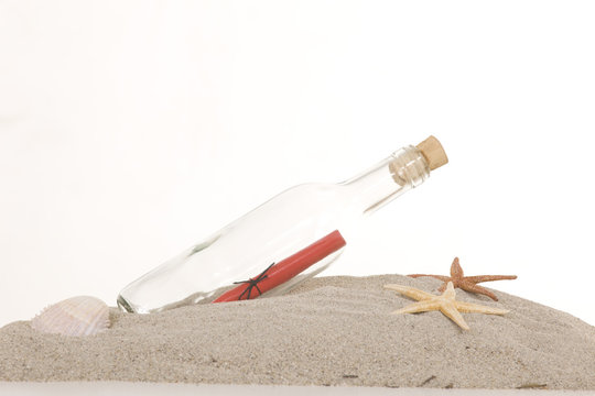 Glass bottle with note inside on sand, on white background