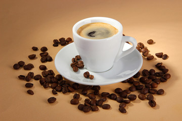 Cup of coffee with coffee beans on beige background
