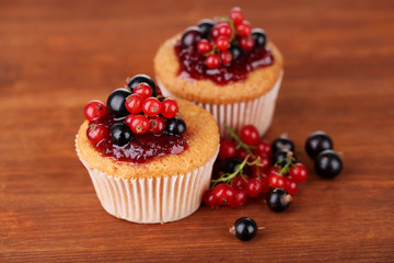 Tasty muffins with berries on wooden background