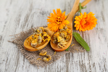 Fresh and dried calendula flowers on wooden background
