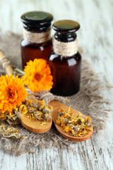 Medicine bottles and calendula flowers on wooden background