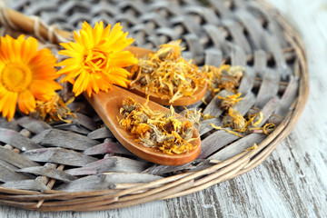 Fresh and dried calendula flowers on wooden background