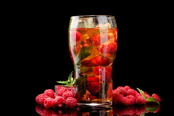Iced tea with raspberries and mint on black background